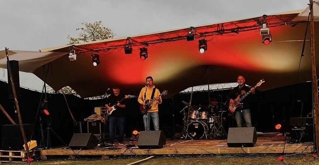 Photo du groupe de rock Les Welshers sur une scène au crépuscule.