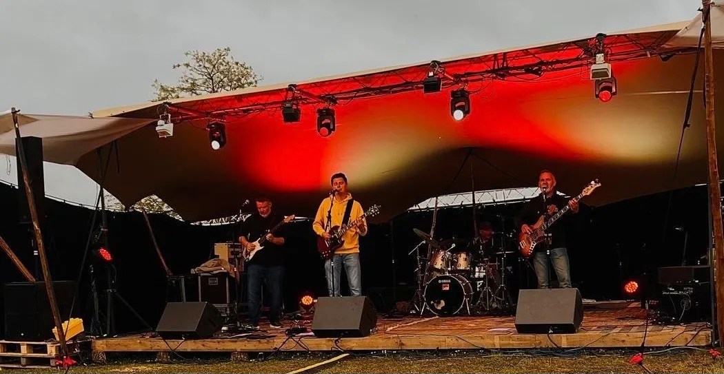 Photo du groupe de rock Les Welshers sur une scène au crépuscule.